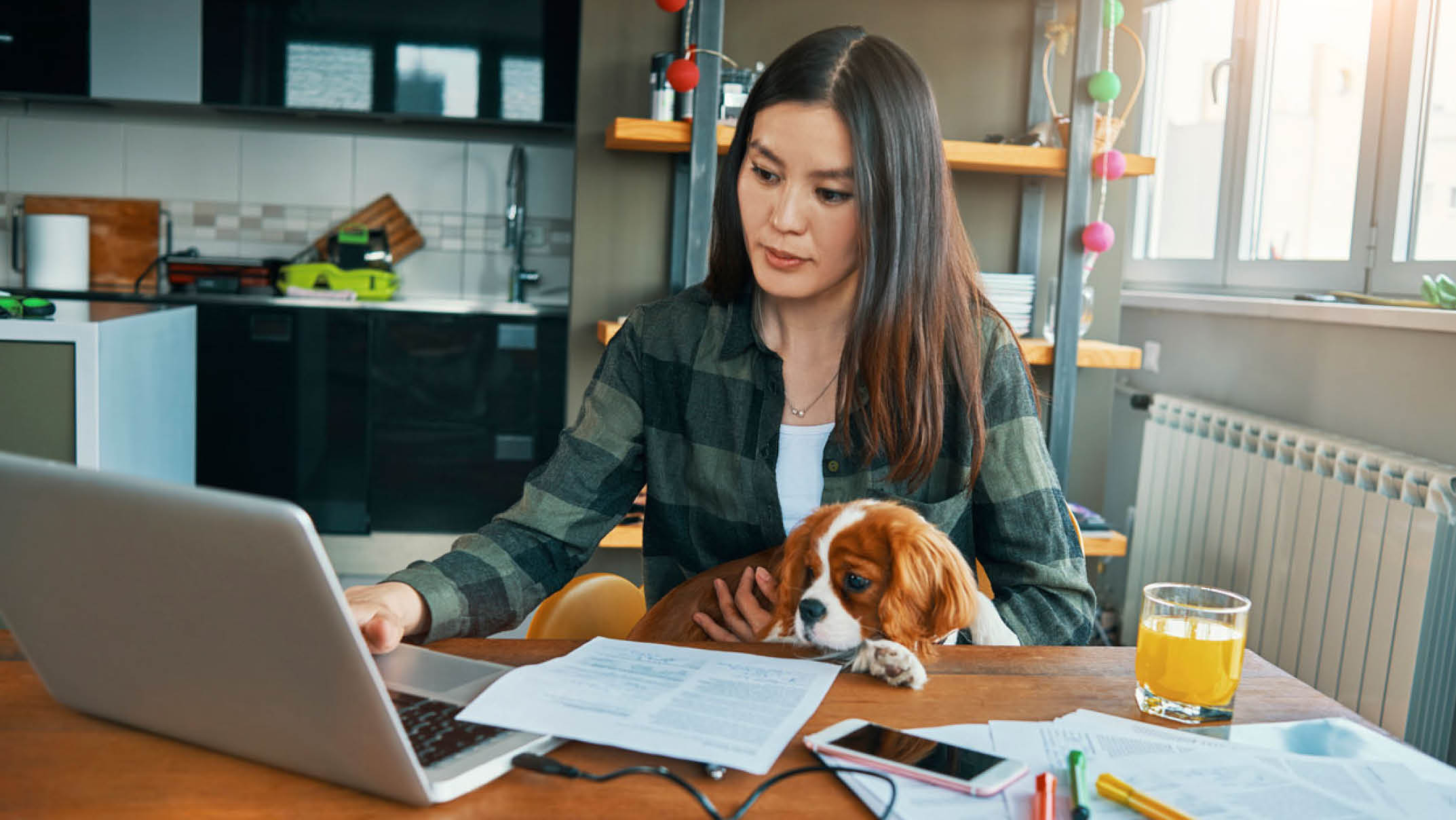 Female Working from Home with a Puppy on her Lap and on her Laptop