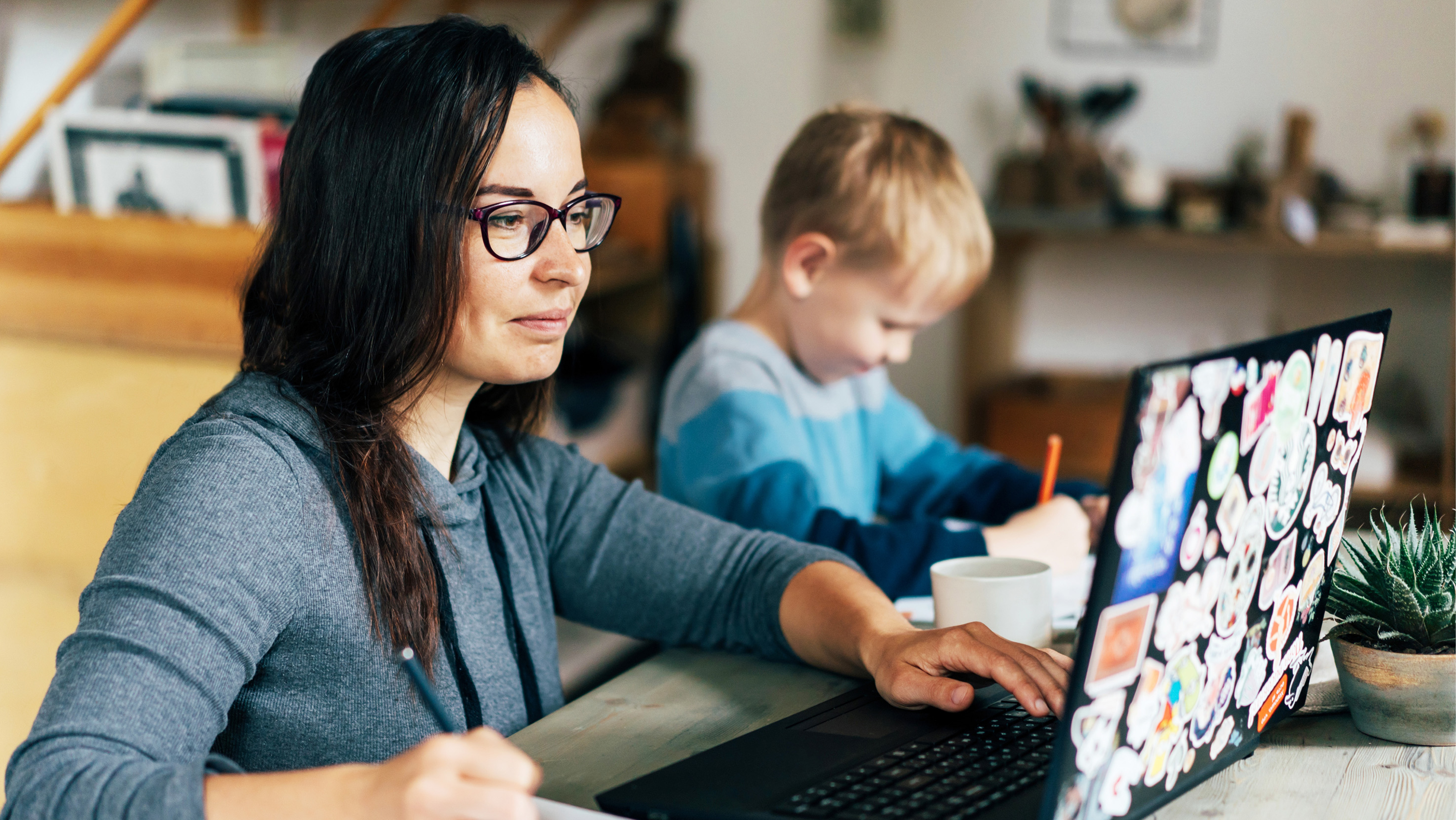 Mother working on laptop next to her child